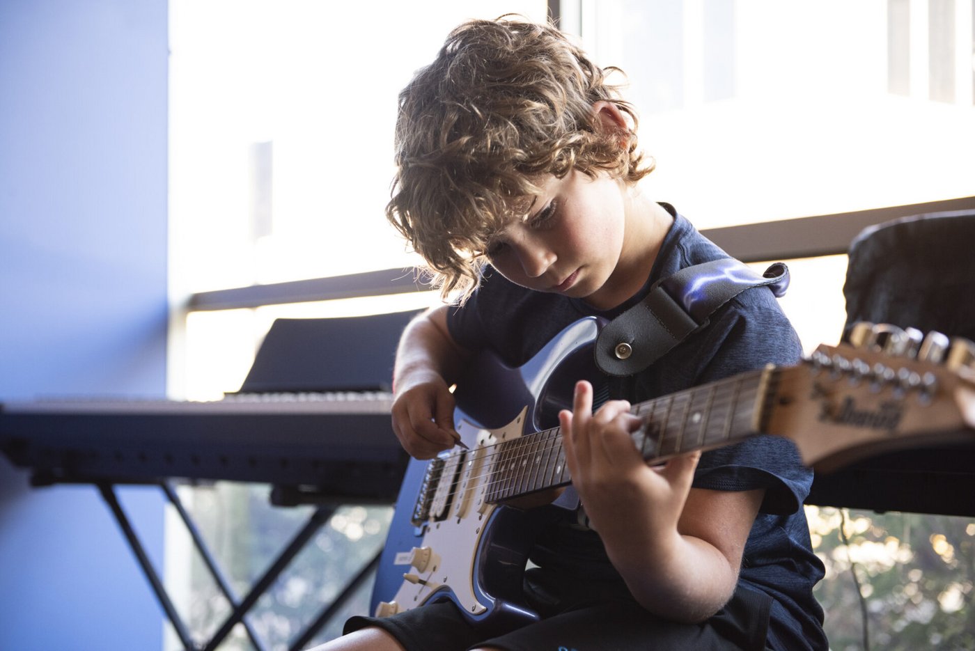 A student practicing electric guitar during a lesson
